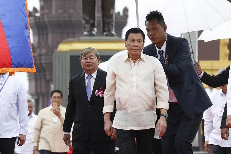 Mr Duterte (centre) at the monument of the late King Norodom Sihanouk in Phnom Penh yesterday, with the statue of the late King behind him. The Philippine leader was there to lay wreaths and pay his respects. Cambodian students lining the streets to 
