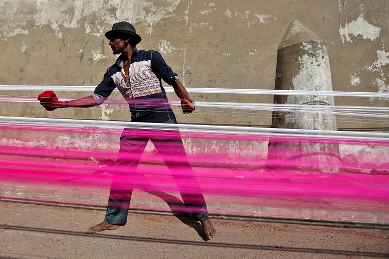 A worker in India applying colour to strings used to fly kites. A UN report has revealed that global wage growth has slowed significantly, especially in developing nations. This has raised fears of growing inequality worldwide.