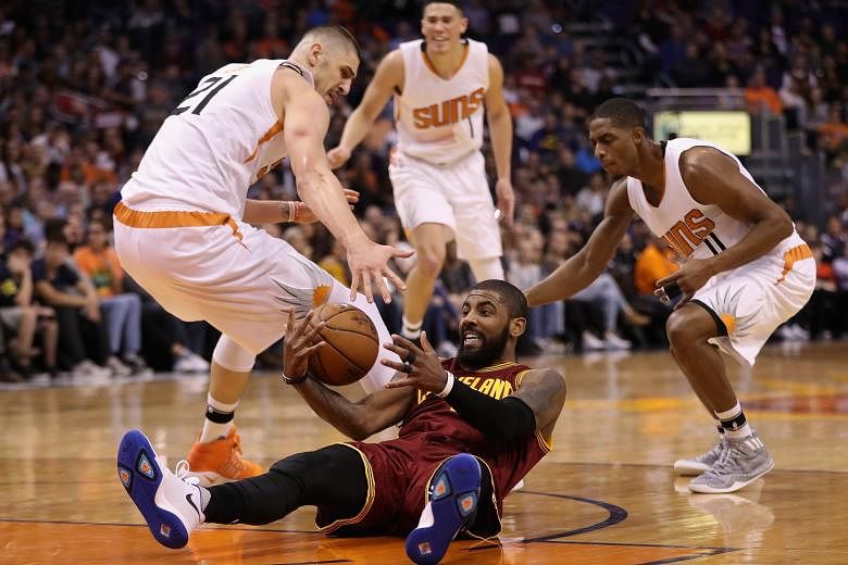 Cleveland's Kyrie Irving beating (from left) Phoenix's Alex Len, Devin Booker and Brandon Knight to recover a turnover in their NBA game. The Cavs enjoyed big leads at the end of each of the first three quarters but had to fend off the Suns' late com