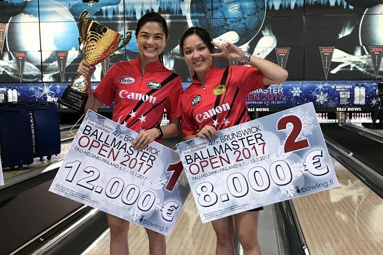 Daphne Tan (left) holding her Brunswick Ballmaster Open trophy and prize money beside runner-up Jazreel Tan.
