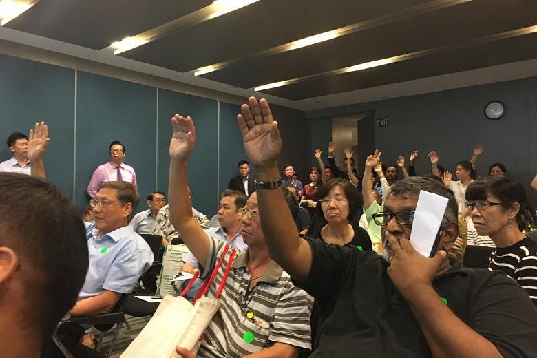 Shareholders and proxy holders of International Healthway Corp voting by a show of hands to adjourn the meeting, held at Maxwell Chambers, yesterday. The adjournment was voted down narrowly, 63 to 58.