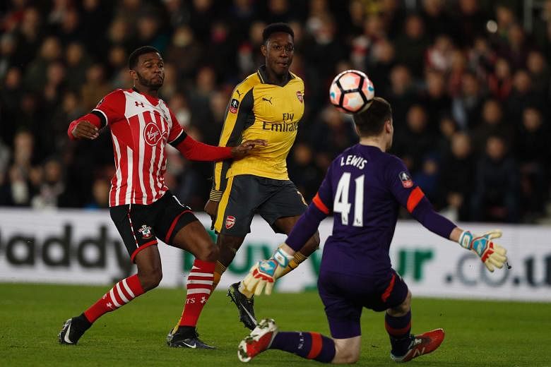 Danny Welbeck (centre) chips the ball over Southampton goalkeeper Harry Lewis to score Arsenal's opener. Welbeck scored a brace as the Gunners won 5-0 away in the fourth round of the FA Cup and now turn their attention to the Premier League, with a c