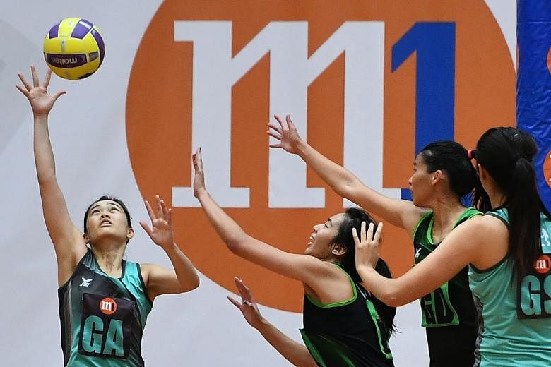 Tiger Sharks' Zhang Ailin (left) reaching for the ball during the Netball Super League opening match at Toa Payoh Sports Hall yesterday. The Sharks, who have six national players, beat the Magic Marlins 54-48.