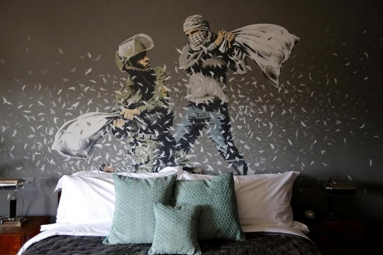 Above a bed in The Walled Off Hotel, an Israeli soldier and a Palestinian protester fight with pillows.