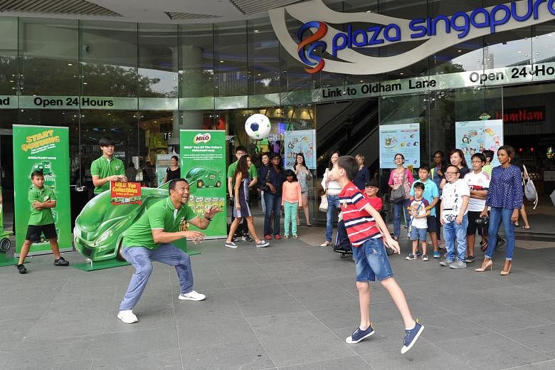Singapore football legend Fandi Ahmad with one of the fans yesterday at Plaza Singapura as part of a promotional campaign with Milo. Fandi was joined by his daughter Iman and son Iryan.