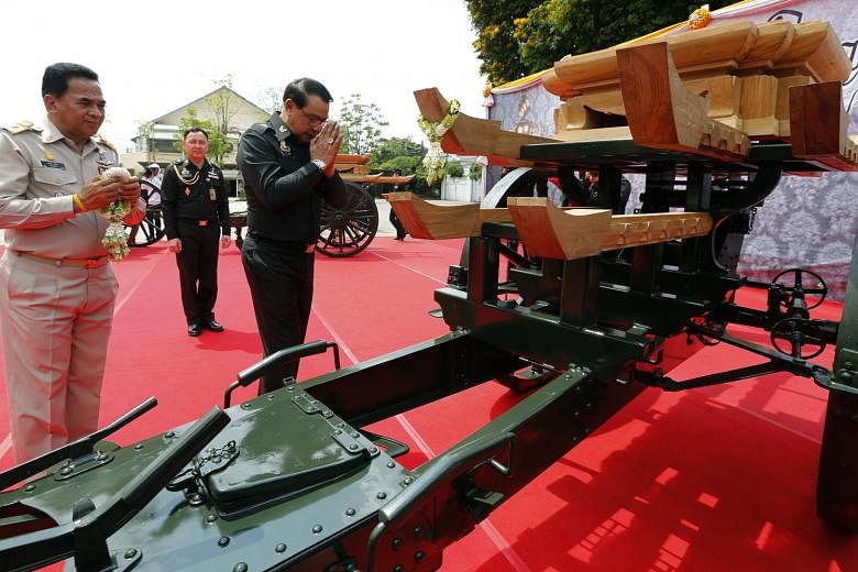 Members of the Royal Thai Army paying their respects in front of an artillery chariot which will be part of the late Thai King's funeral procession later this year.