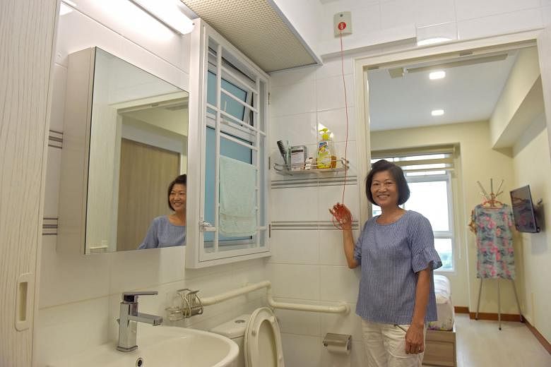 Retired cashier Julie Lee, 60, with an emergency toilet alarm in her studio flat at Kallang Trivista. The alarm sends a signal to the seniors' activity centre downstairs. 