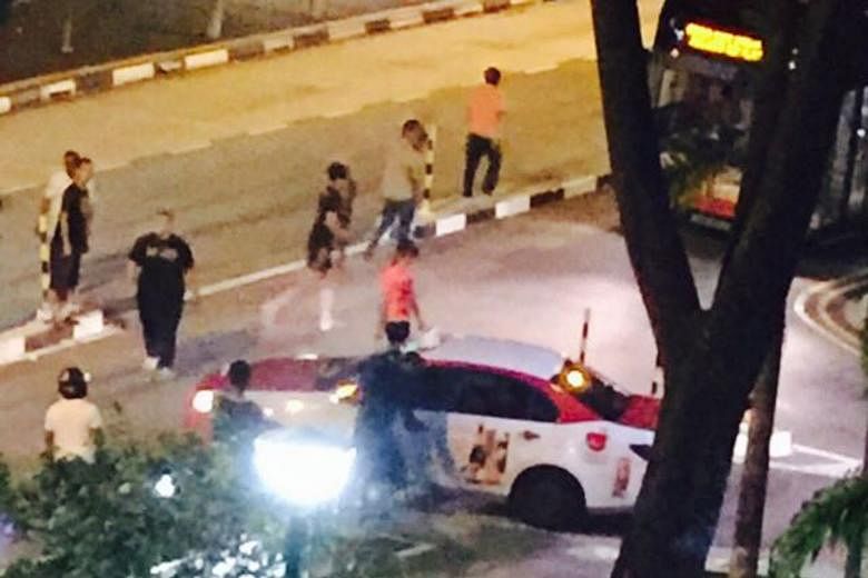 Passers-by helping to move a cab that was stuck on a road divider in Choa Chu Kang Avenue 5 last Friday night. The taxi was successfully moved only after about 10 people gathered to help.