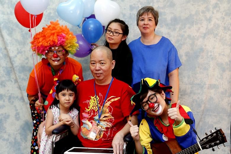 Mr Esmond Goh, with his wife Joanne Lio and daughters Lucia, six, and Lois, 12, having their family photo taken with HCA Hospice Care volunteers, who doubled up as make-up artists, clowns and chaperones.