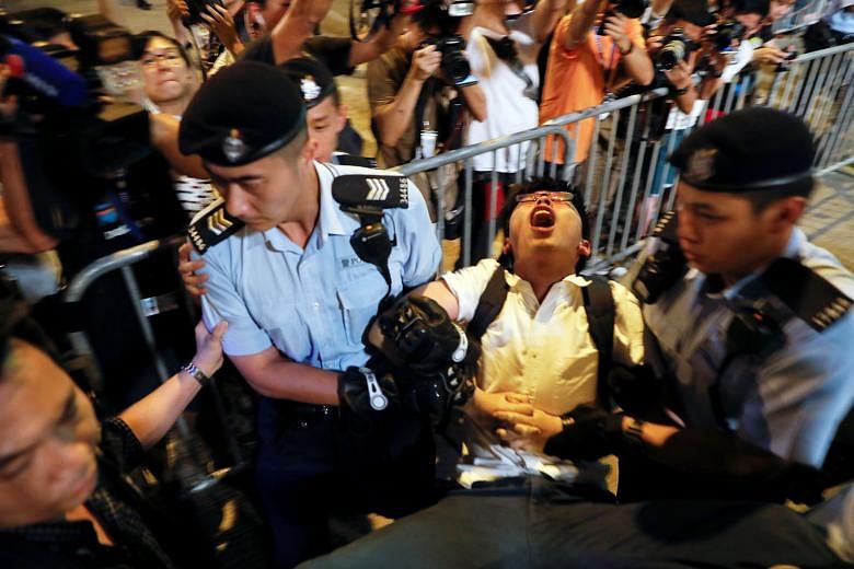 Hong Kong student protest leader Joshua Wong being removed by policemen on Wednesday, at a monument symbolising the city's handover from British to Chinese rule, a day before Chinese President Xi Jinping was due to arrive for celebrations to mark the