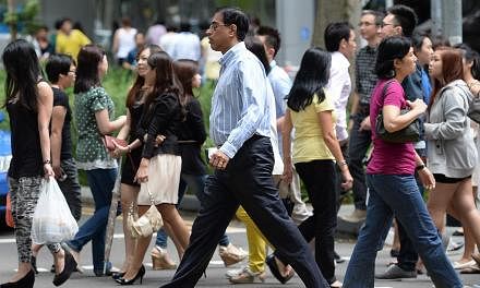 Office workers and pedestrians crossing the road at Raffles Place.&nbsp;Singapore's economy is gradually regaining its upward momentum as the developed nations recover, prompting the central bank to tip "modest growth" for the local economy this year