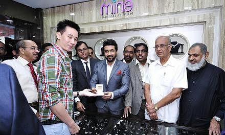 Indian actor Suriya handing over an item to a customer on the opening day of Malabar Gold & Diamonds' store in Syed Alwi Road. Malabar has its sights set on being the world's No. 1 jewellery retailer by 2015.