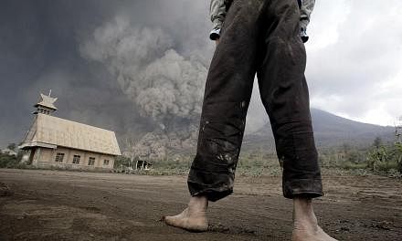 A resident looks on at giant volcanic ash clouds from a village in Karo district during the eruption of Mount Sinabung volcano located in Indonesia's Sumatra island on February 1, 2014. Fourteen people, including four schoolchildren, were killed Febr