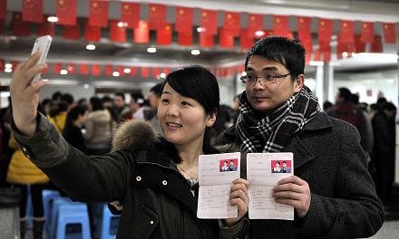 A couple pose for pictures with their marriage certificates at a civil affairs bureau in Hefei, Anhui province, on February 14, 2014. According to local media, many young couples rushed to register their marriages on Friday as the last day of Chinese