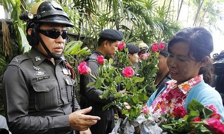 A military rule supporter hands roses to policemen guarding the Australian embassy in Bangkok June 4, 2014. -- PHOTO: REUTERS