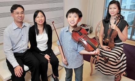 Young violinist Samuel Tan enjoys going for competitions because they offer him a chance to see other people playing the instrument. With him are his parents Jason Tan and Janis Low (both left) and his teacher Lee Huei Min.