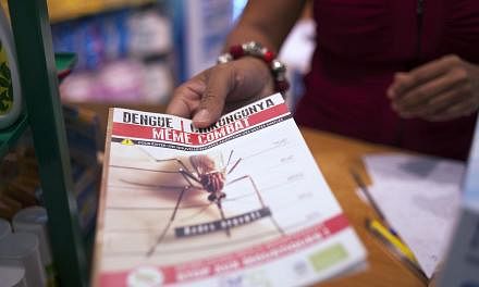 A picture taken on July 10, 2014, shows a shopkeeper handing to a customer some documentation about the mosquito-born chikungunya virus at a drugstore in Lamentin, near Fort-de-France, on the French Caribbean island of La Martinique.&nbsp;-- PHOTO: A
