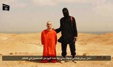 A masked Islamic State militant holding a knife speaks next to man purported to be US journalist James Foley at an unknown location in this still image from an undated video posted on a social media website. Foley's&nbsp;mother said on Tuesday that h