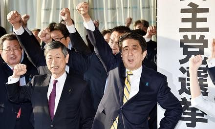 Japan's Prime Minister and leader of the ruling Liberal Democratic Party (LDP) Shinzo Abe (centre, right) raises his fist in the air to shout with his party's lawmakers as they open an election campaign office at the LDP headquarters in Tokyo on Nov 