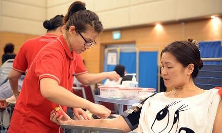 Miss Deslyn Lee, 44, a SPH staff from Classified, is donating her blood for the 11th time with SPH Blood Donation Drive with the help of Blood Bank nurse, Miss Ho Xin Xia, Avelina, 28. -- ST PHOTO: DANIEL NEO