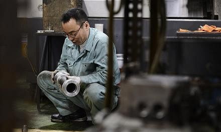 An employee inspecting a machined component at a Kyokuto Seiki Seisakusho K.K. metal machining factory in the Ota ward of Tokyo, Japan, on Dec 5, 2014. -- PHOTO: BLOOMBERG&nbsp;