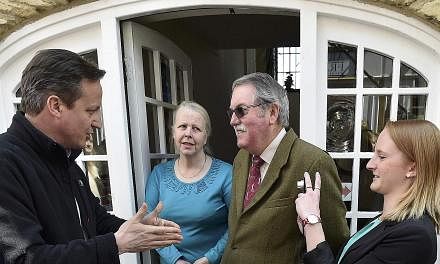 Britain's Prime Minister David Cameron (left) speaks with locals during a 'walkabout' whilst campaigning in Wetherby in northern England, Britain, April 30, 2015. A feisty audience grilled Britain's political leaders on Thursday over what deals and c