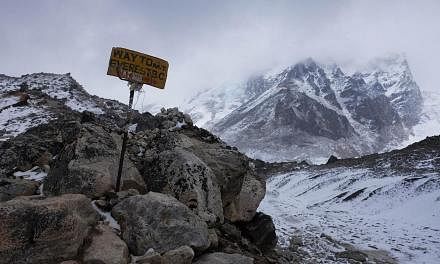 A sign showing the way to Everest Base Camp high in the Khumb Glacier stands among rocks on April 26, 2015, one day after an earthquake triggered avalanche swept through parts of the base camp killing scores of people. -- PHOTO: AFP