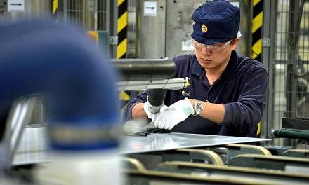 An employee works on solar panels on the module production line at the REC Solar ASA manufacturing facility in Tuas on Sept 5, 2014. Singapore's manufacturing PMI for April will be released on Monday, May 4, 2015. -- PHOTO: ST FILE