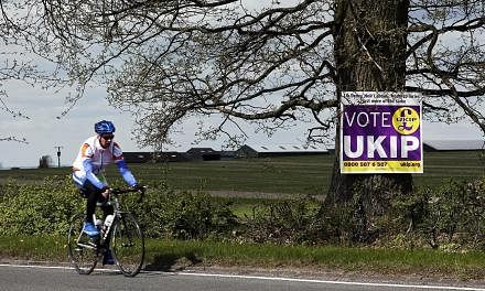 A cyclist riding past a UK Independence Party (UKIP) election campaign poster on the outskirts of Aylesbury, north-west of London, on April 30, 2015. UKIP candidate Robert Blay has been suspended after a video of him insulting Conservative rival Rani