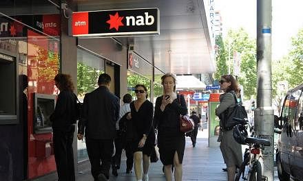 People walking past and queueing at the National Australia Bank (NAB) ATM machine. -- PHOTO: BLOOMBERG