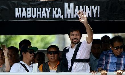 Boxing icon Manny Pacquiao (2nd right) of the Philippines waves to his supporters during a welcome parade in Manila on May 13, 2015. -- PHOTO: AFP