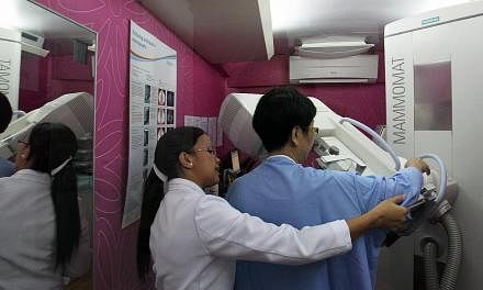 A National Healthcare Group radiographer (in white) preparing a woman for a mammogram. -- PHOTO: ST FILE