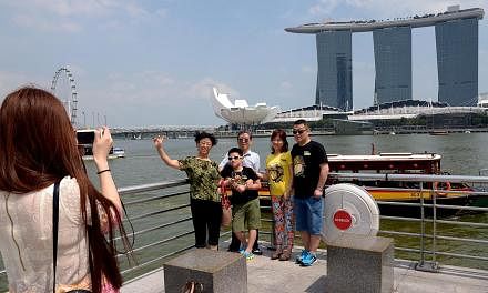 A lady taking a group photograph for tourists from China at the Merlion. It will be less of a hassle for some travellers from China to visit Singapore from June 1. -- ST PHOTO: LIM SIN THAI&nbsp;