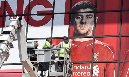 Workers pasting a poster over Liverpool's English midfielder Steven Gerrard as they replace sections of a mural outside The Kop stand at Anfield, Liverpool, north-west England on May 13, 2015. -- PHOTO: AFP