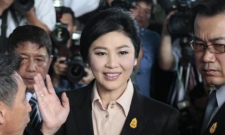 Thailand's ousted prime minister Yingluck Shinawatra (centre) greeting well-wishers and supporters as she arrives at the Supreme Court to face charges of corruption over a rice subsidy plan, in Bangkok, on May 19, 2015. -- PHOTO: EPA&nbsp;