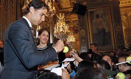 Rafael Nadal (left) autographs tennis balls for supporters after receiving the Vermeil Medal of the City of Paris on May 21, 2015 in Paris. -- PHOTO: AFP&nbsp;