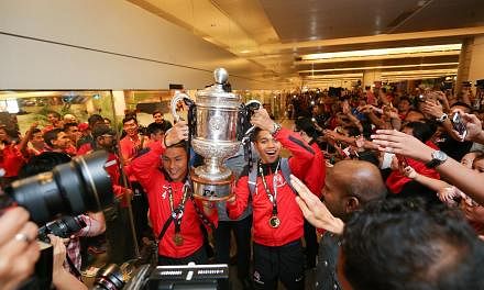 LionsXII captain Isa Halim and vice-captain Izwan Mahbud holding the Malaysian FA Cup trophy as the team enters the arrival hall of Changi Airport Terminal 2 on Sunday evening. -- ST PHOTO: ONG WEE JIN&nbsp;