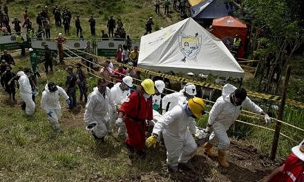 Forensic personnel and rescue workers carry the corpse of one of the fifteen miners who were trapped by the collapse of a gold mine, near the area of El Saibo, in Riosucio, Caldas department, Colombia, on May 15, 2015. -- PHOTO: AFP&nbsp;