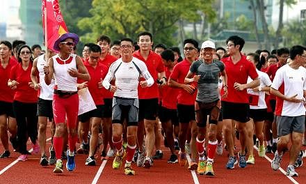 Pacer Gerrard Lin bearing the SEA Games flag as Mr Yong Yuen Cheng (centre, in white) and Mr Lim Nghee Huat (in grey) ran with students in Hwa Chong Institution yesterday.