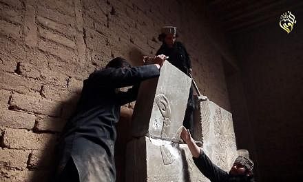 An image grab taken from a video made available by Jihadist media outlet Welayat Nineveh on April 11, 2015, allegedly shows members of the Islamic State (IS) militant group destroying a stoneslab with a sledgehammer at what they said was the ancient 