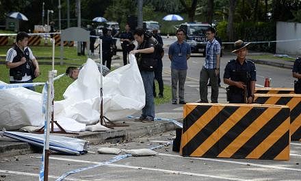Members of the Singapore Police Force inspecting the site of a shooting at the junction of Orange Grove Road and Anderson Road, where a man was shot dead and two others were arrested after a car illegally bypassed a police vehicular checkpoint, early