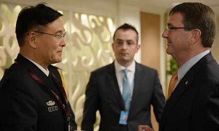 Chinese Deputy Chief, General Staff Department, People's Liberation Army, Admiral Sun Jianguo (left) speaks to United States Secretary of Defense Dr Ashton Carter during the Ministerial Luncheon during the IISS Shangri-La Dialogue on May 31, 2015. --