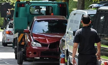 A damaged red car with a bullet hole on its windscreen is being towed away in Singapore near the Shangri-La hotel on May 31, 2015. Two passengers in the car that crashed through police barriers near the Shangri-la Hotel in the wee hours of Sunday wer