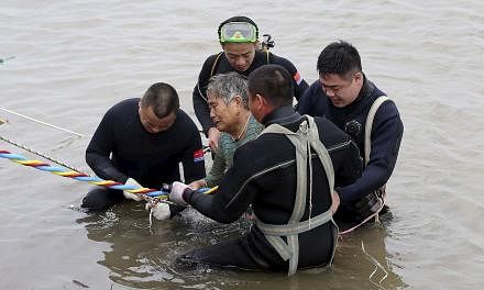 A woman is helped after being pulled out by divers from a capsized ship in Jianli, Hubei province, China on June 2, 2015. Rescuers are working to save five more passengers trapped inside the hull of the ship that capsized in China's Yangtze River&nbs