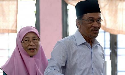 In this file photo taken on May 5, 2013, opposition leader Anwar Ibrahim (right), accompanied by his wife Wan Azizah, casts his vote at a polling station in Permatang Pauh, Penang. -- PHOTO: AFP