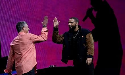 Apple's senior vice president of Internet Software and Services Eddy Cue (left) high-fives Drake during the Apple Music introduction at the Apple WWDC on June 8, 2015, in San Francisco, California. -- PHOTO: AFP