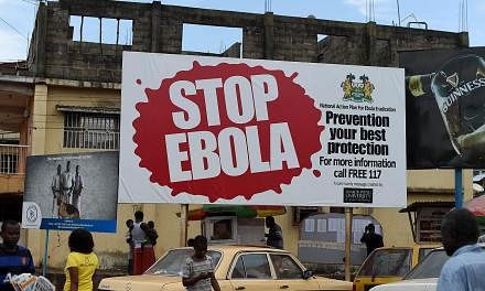 People walking pass a billboard on Ebola in Freetown, Sierra Leone, on Nov 7, 2014. The World Health Organisation on Wendesday, June 10, 2015, reported that the number of Ebola cases in Sierra Leone and Guinea has risen for the second consecutive wee