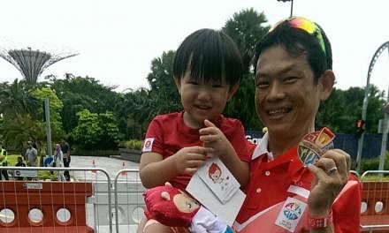 Singapore cyclist Vincent Ang, carrying his son Joshua, with his SEA Games bronze medal in the men's criterium on June 12, 2015. -- ST PHOTO: HO SI RUI&nbsp;