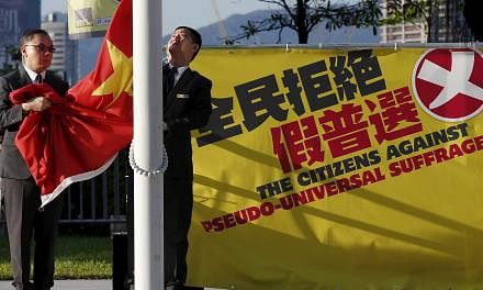 Flagbearers lower a Chinese national flag beside a banner set up by pro-democracy protesters outside Legislative Council in Hong Kong, China on June 16, 2015. -- PHOTO: REUTERS&nbsp;