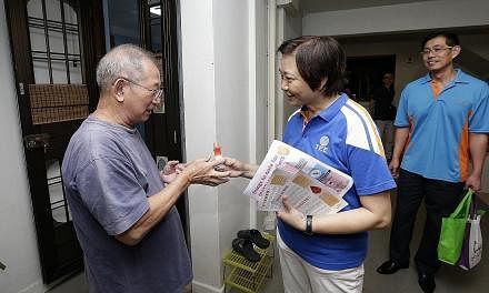 Nee Soon GRC MP Lee Bee Wah giving insect repellent to 71-year-old retiree Goh Han Kiat during her door-to-door visit at Block 826, Yishun Street 81, yesterday.
